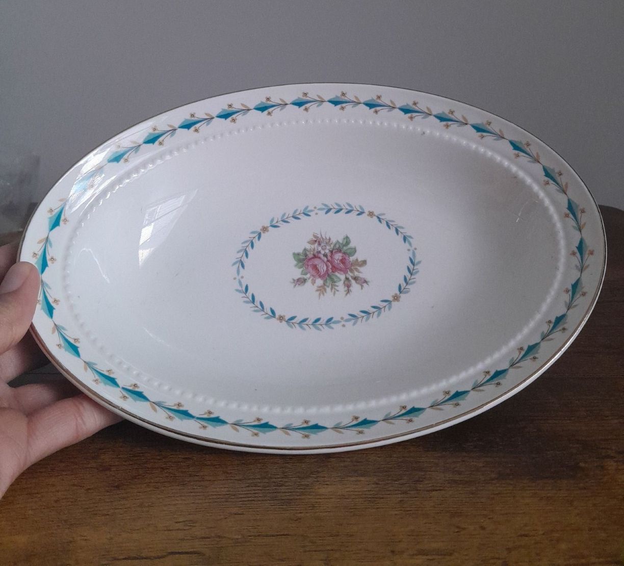 A minimalist, white vintage dish with blue, gold, and pink motifs of flowers.